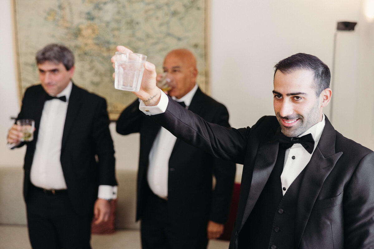 Groom and groomsmen toasting in hotel room before ceremony

