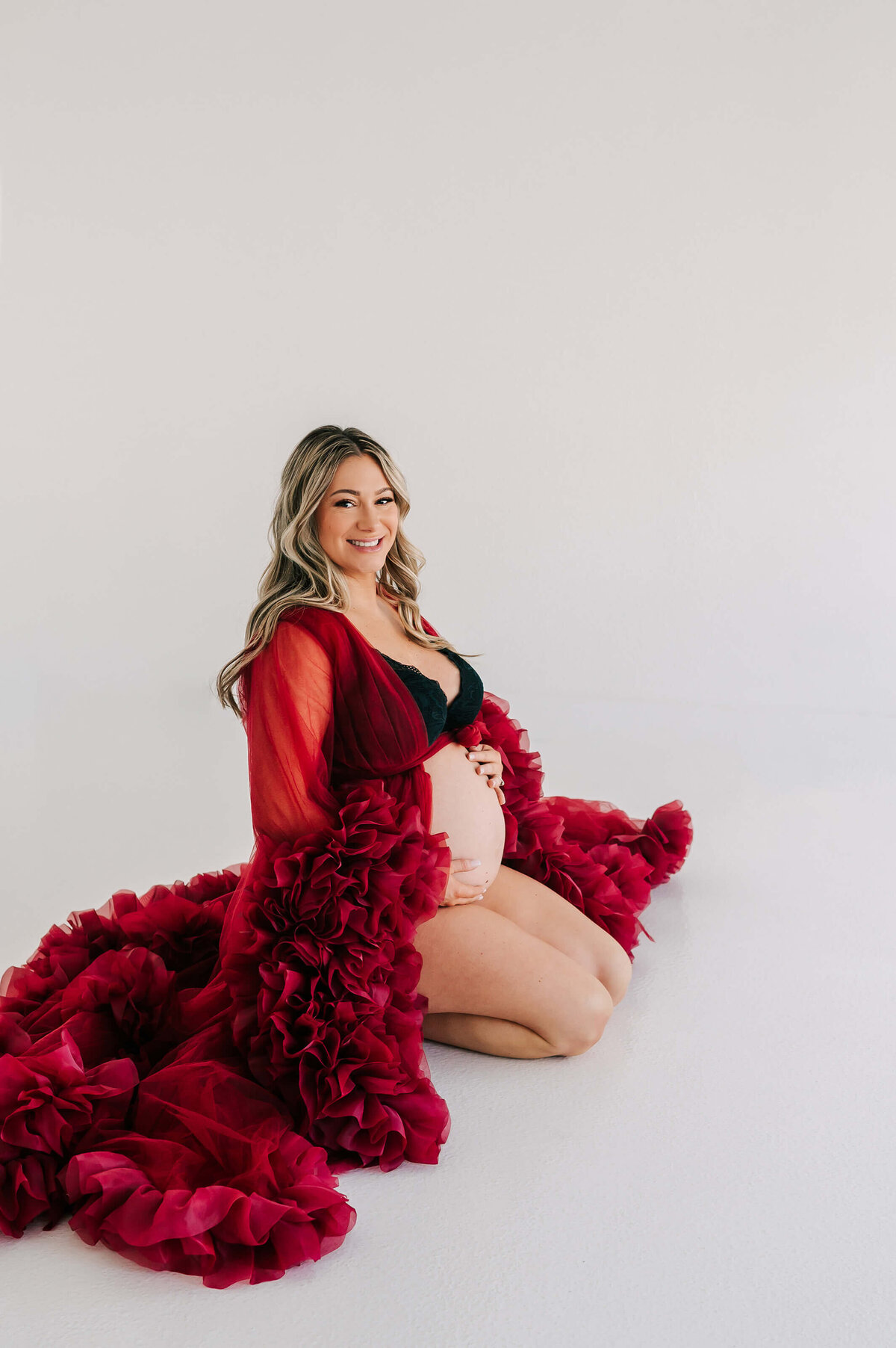 Branson maternity photo of mom kneeling on ground smiling holding baby bump