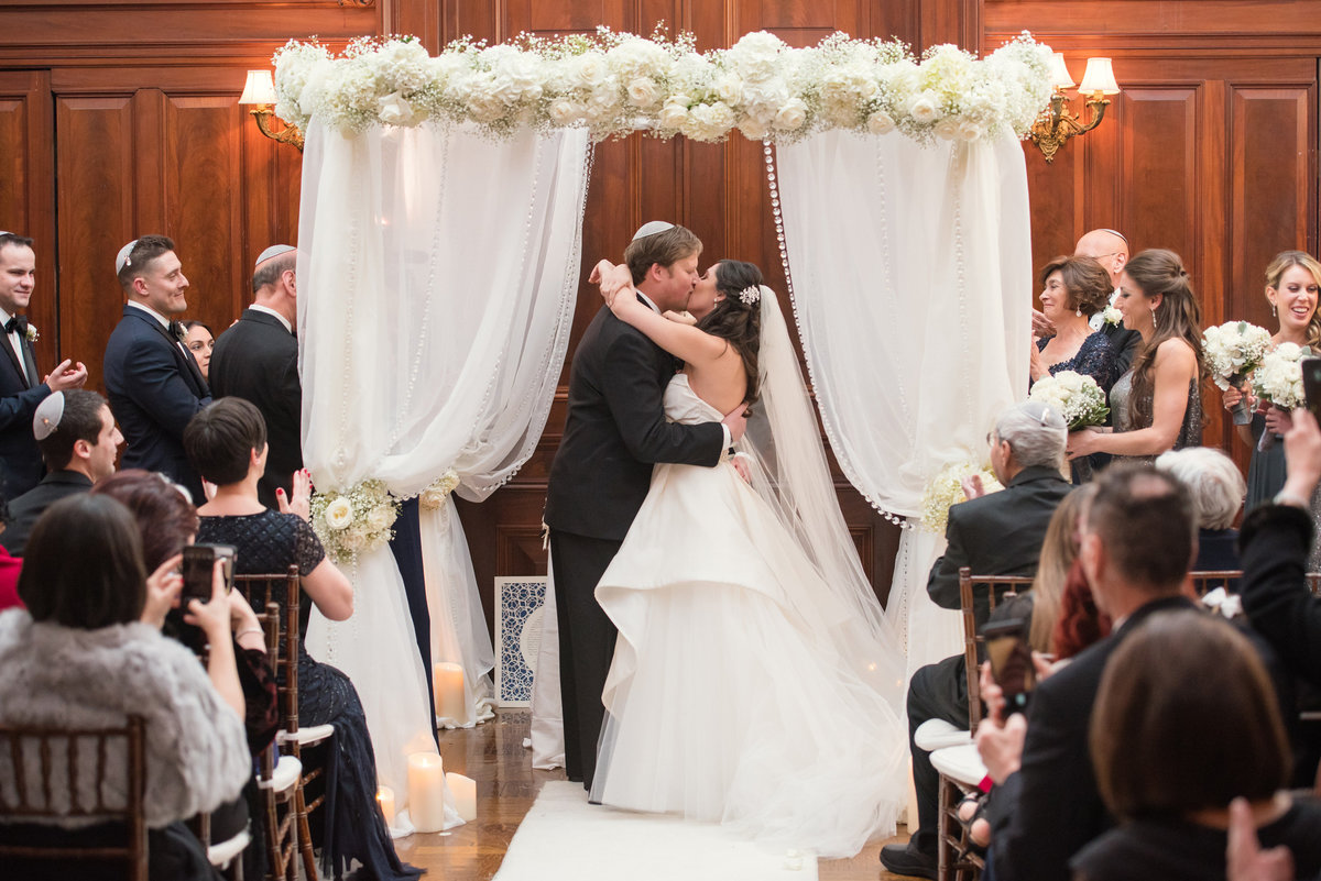 Bride and groom kissing during a wedding ceremony at The Bourne Mansion