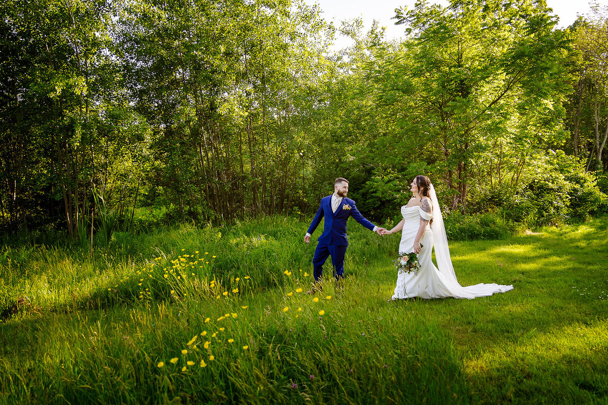 Groom leading bride through field