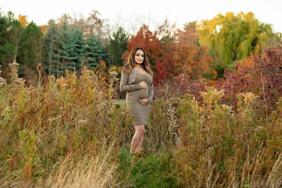 pregnant woman wearing a beige dress for her fall maternity photography session in Burlington, On
