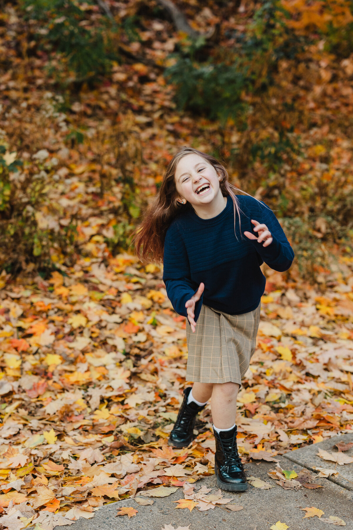 A child runs happily surrounded by fall foliage.