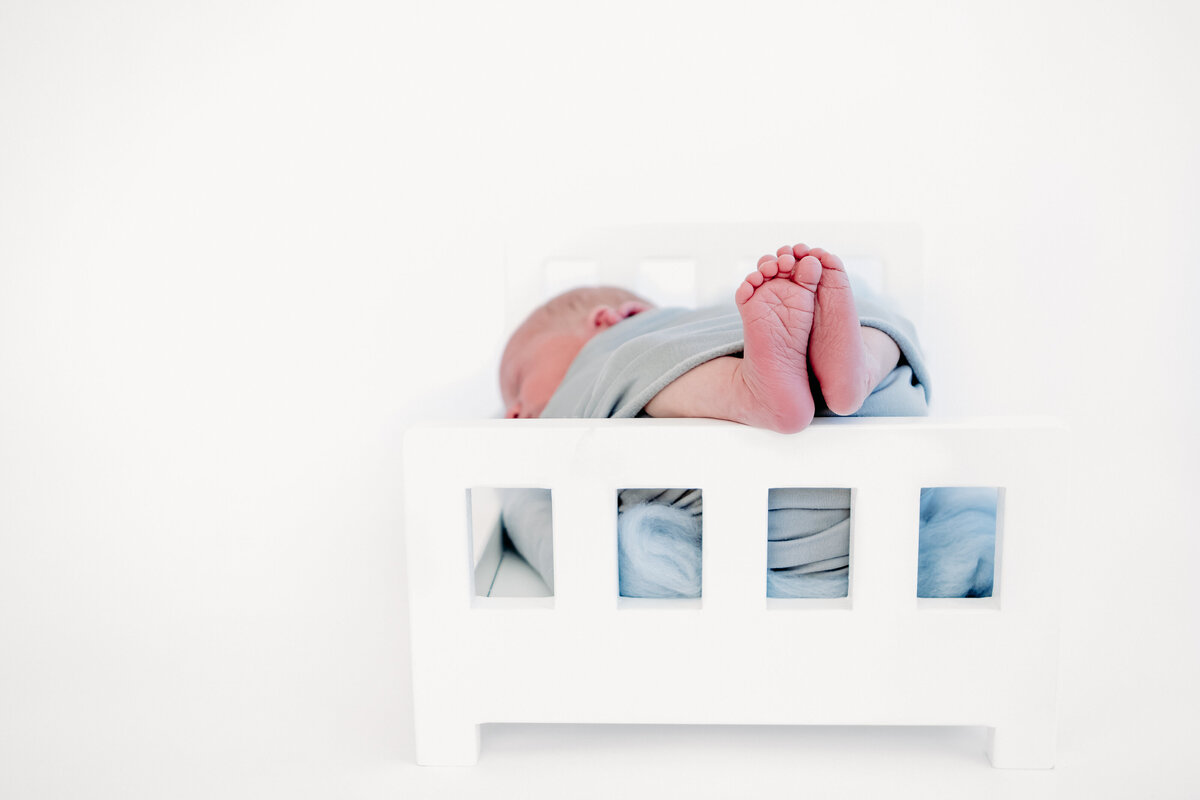 Newborn feet posed on a prop bed during a newborn photography session with Lauren Vanier Photography