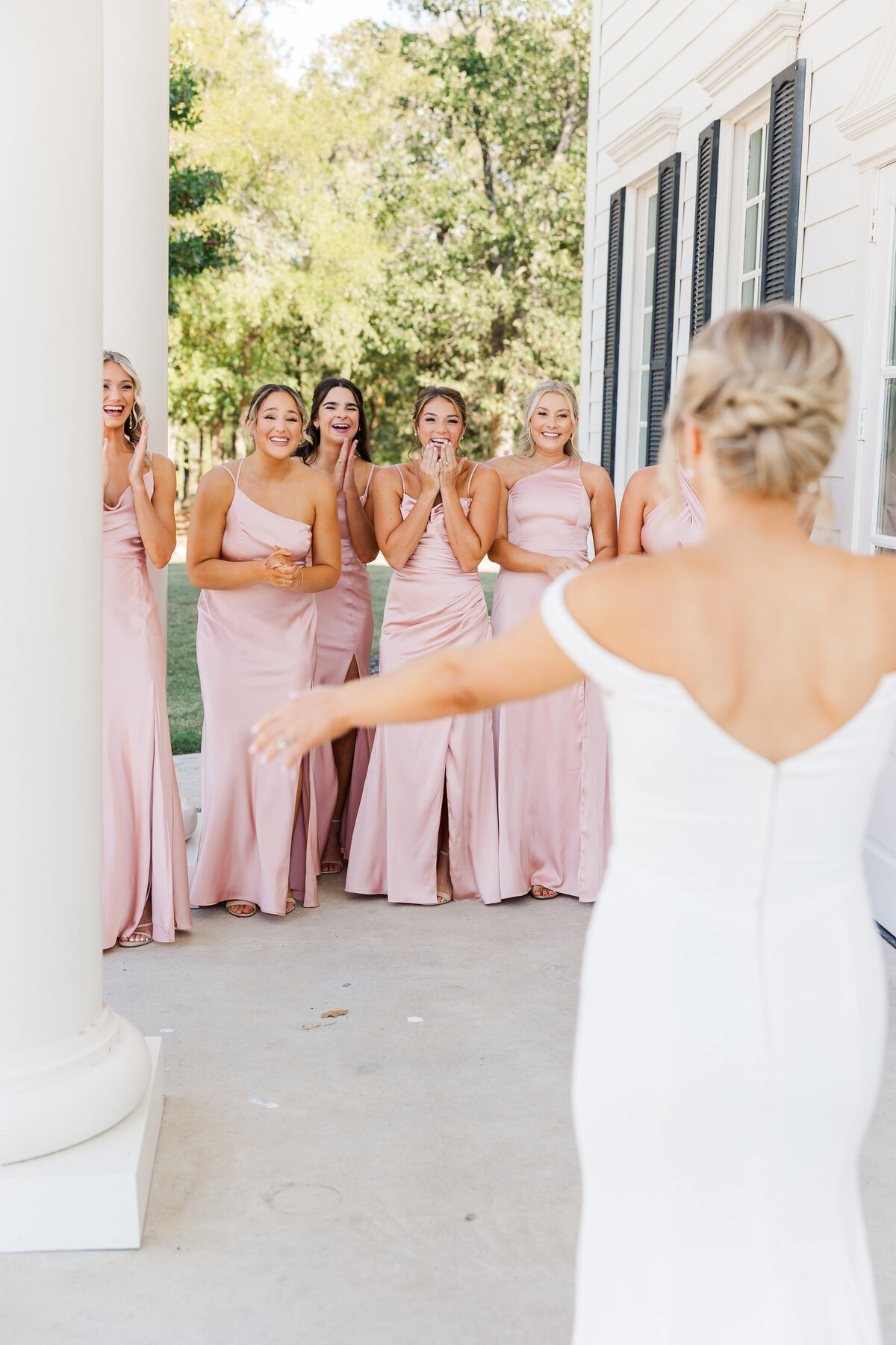 A heartwarming reaction from the bridal party during a first look moment outside a classic Texas wedding estate near Flower Mound. Genuine excitement and soft pink tones bring a touch of elegance and emotion to this unforgettable scene.