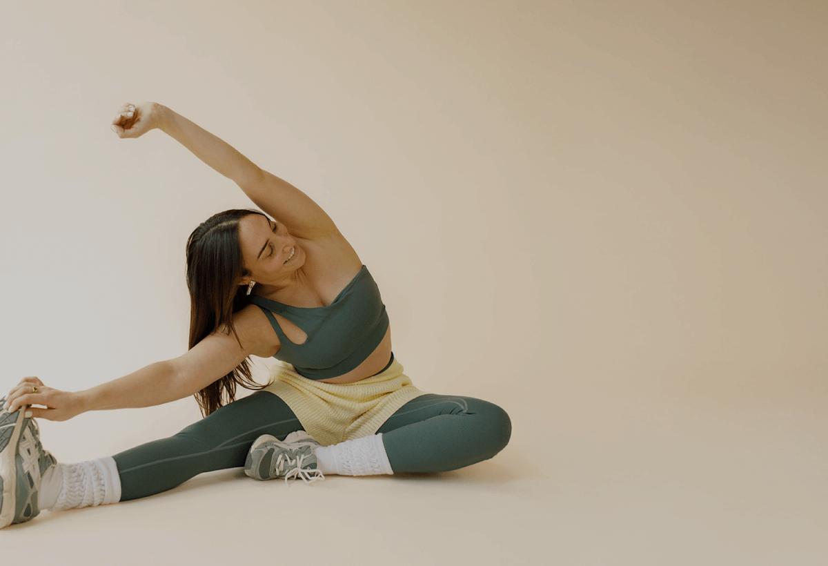Woman fitness instructor sitting on the ground stretching. 