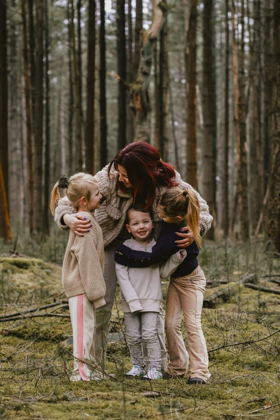 Een liefdevol portret van een moeder met haar kinderen in een bos, met de nadruk op hun omhelzing