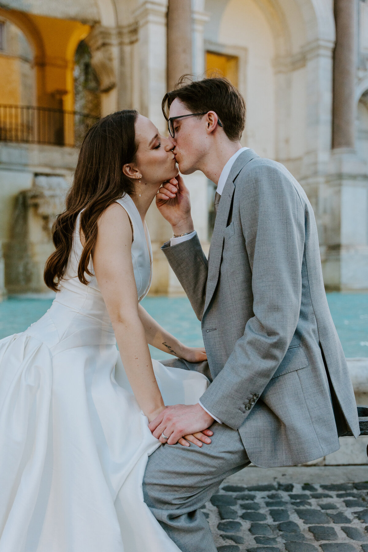 Bride and groom kissing at sunset overlooking Rome.