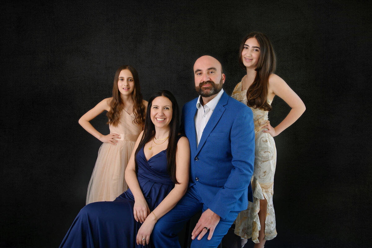 Up-close family photo on a black background of mom and dad and two daughters in Burlington, ON