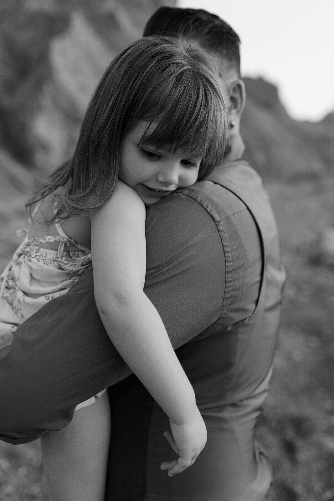 Man holding young child at family with two kids on the beach at family photo shoot in Finger Lakes, NY