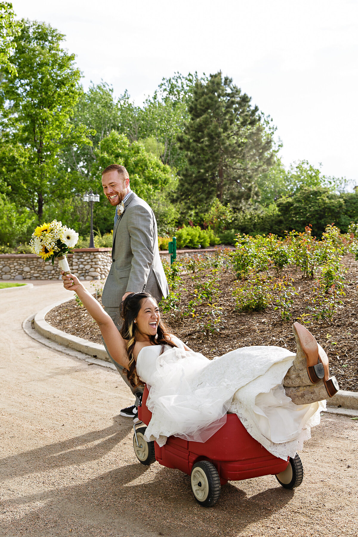 bride-pulled-in-wagon-by-groom-fun-wedding-photography-hudson-gardens-colorado