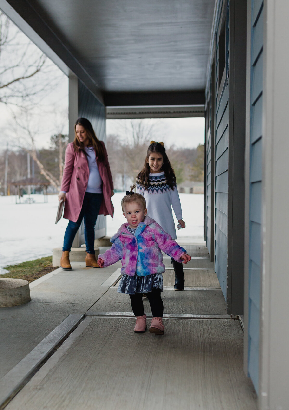 A mom, and two daughters walk outside.