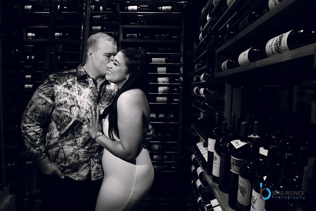 A couple kisses in a wine cellar.