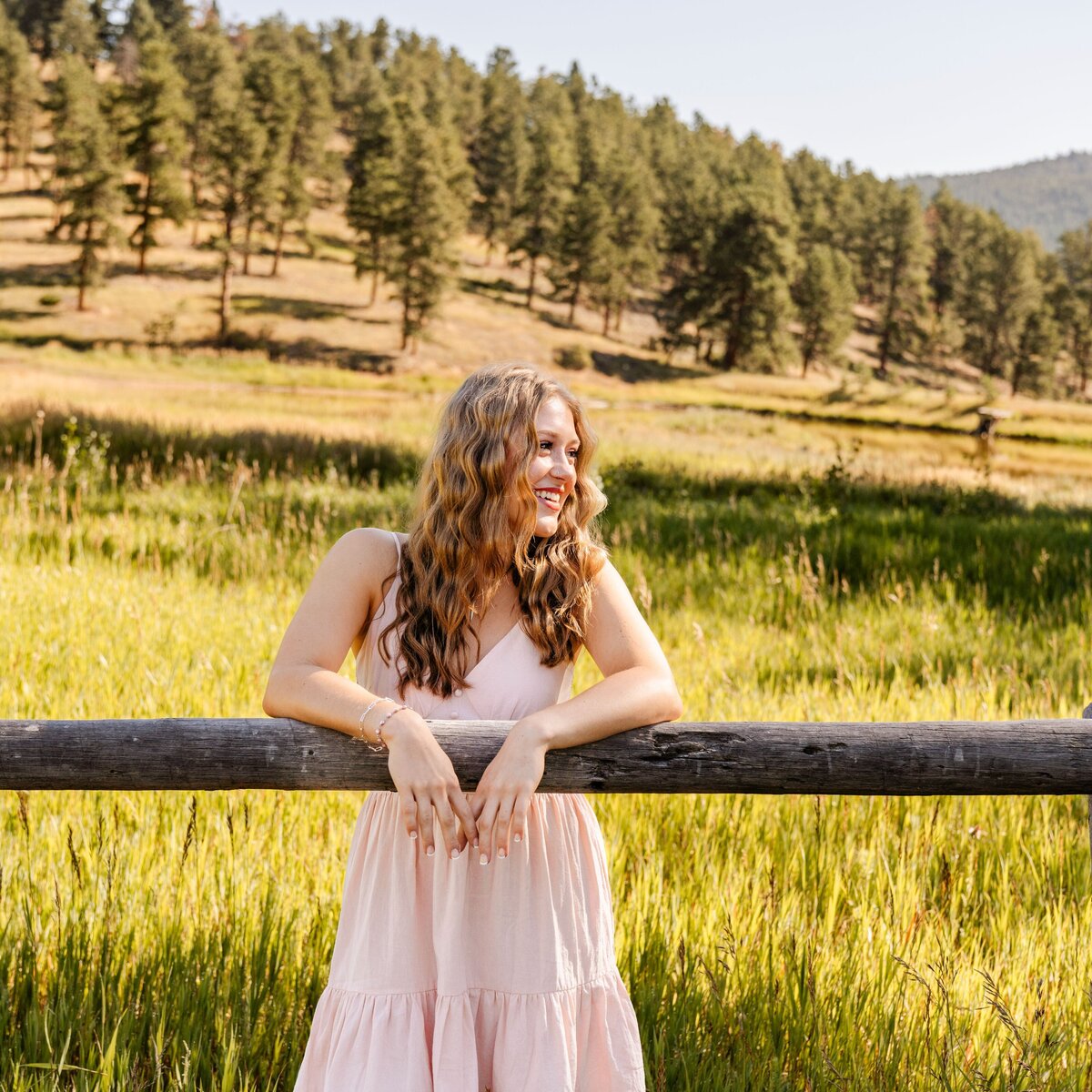 girl smiling with arms folded over fence