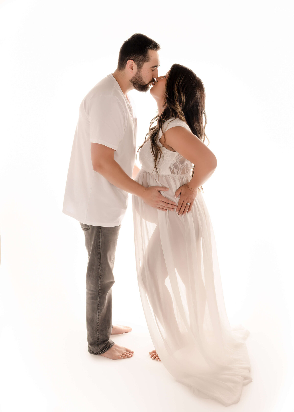 Couple embraced and kissing during in studio maternity session by Ashley Nicole.