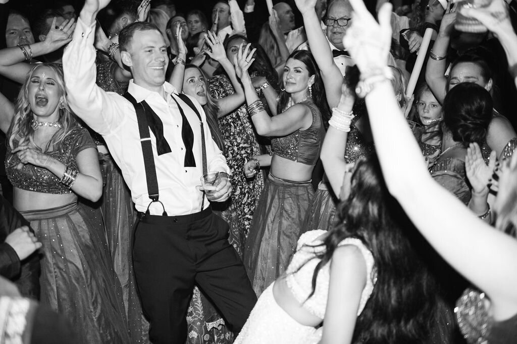 Guests dancing around the newlyweds during the reception at Old Edwards Inn in Highlands, NC, celebrating with glow sticks on the dance floor.