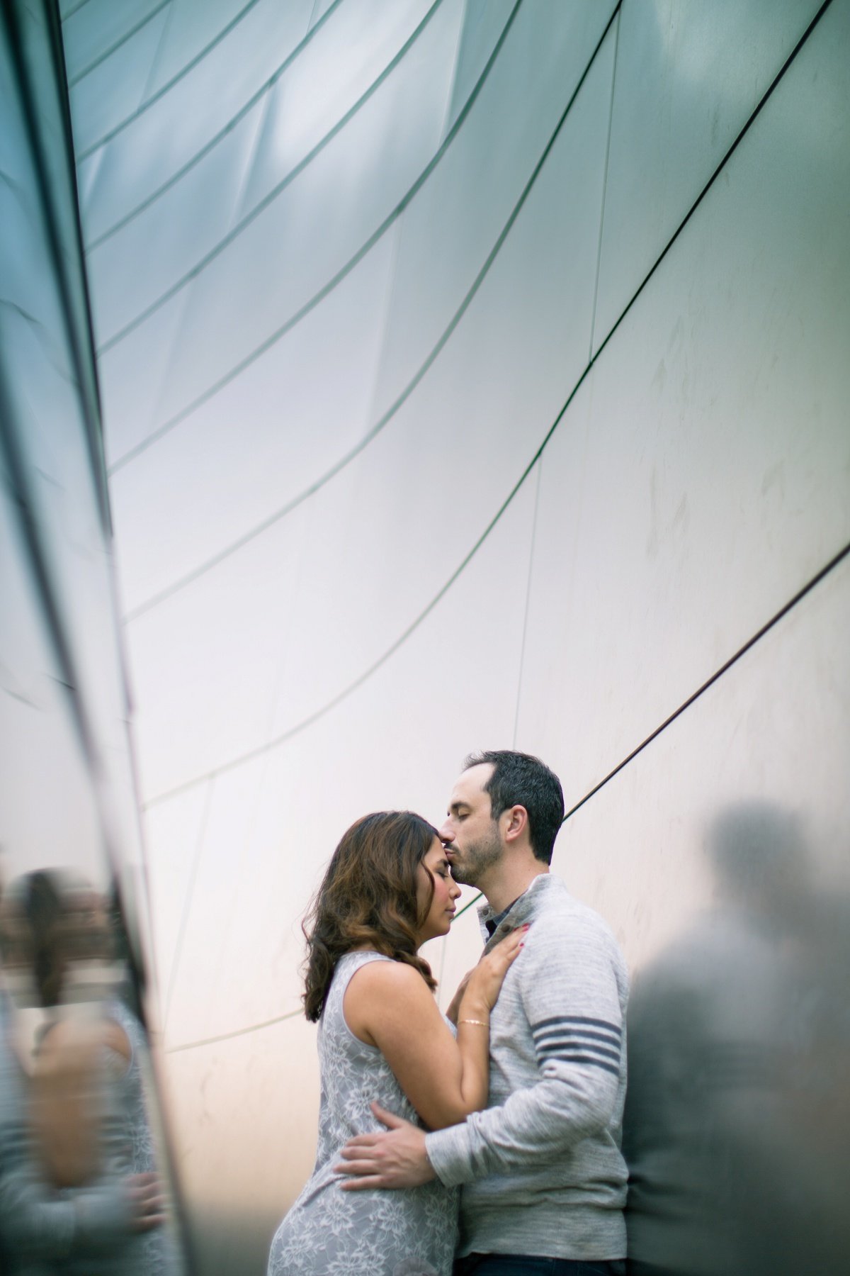 Groom to be kisses his Bride's forehead as they cozy up to each other during an engagement photo session at Walt Disney Concert Hall in Los Angeles