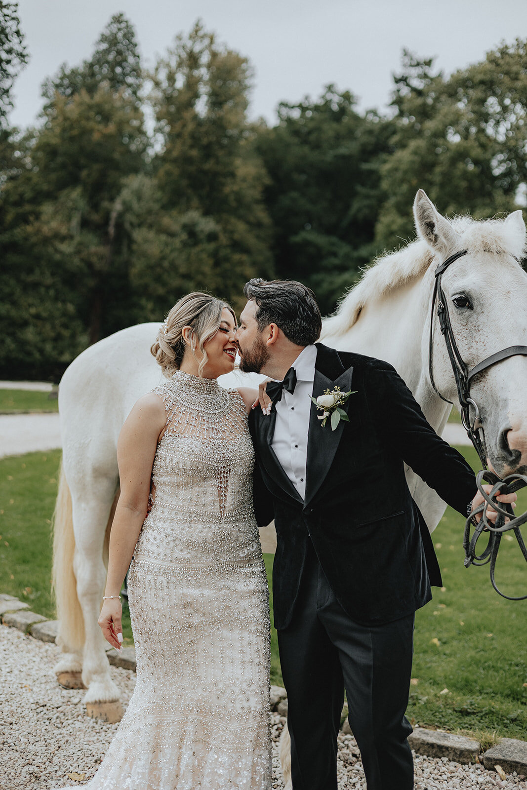 Bride and groom kissing next to white horse