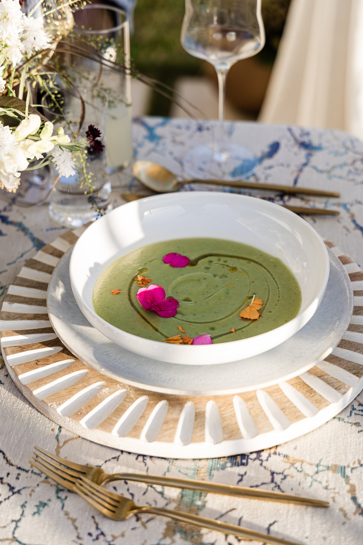 cucumber gazpacho garnished with edible flowers in white pasta bowl