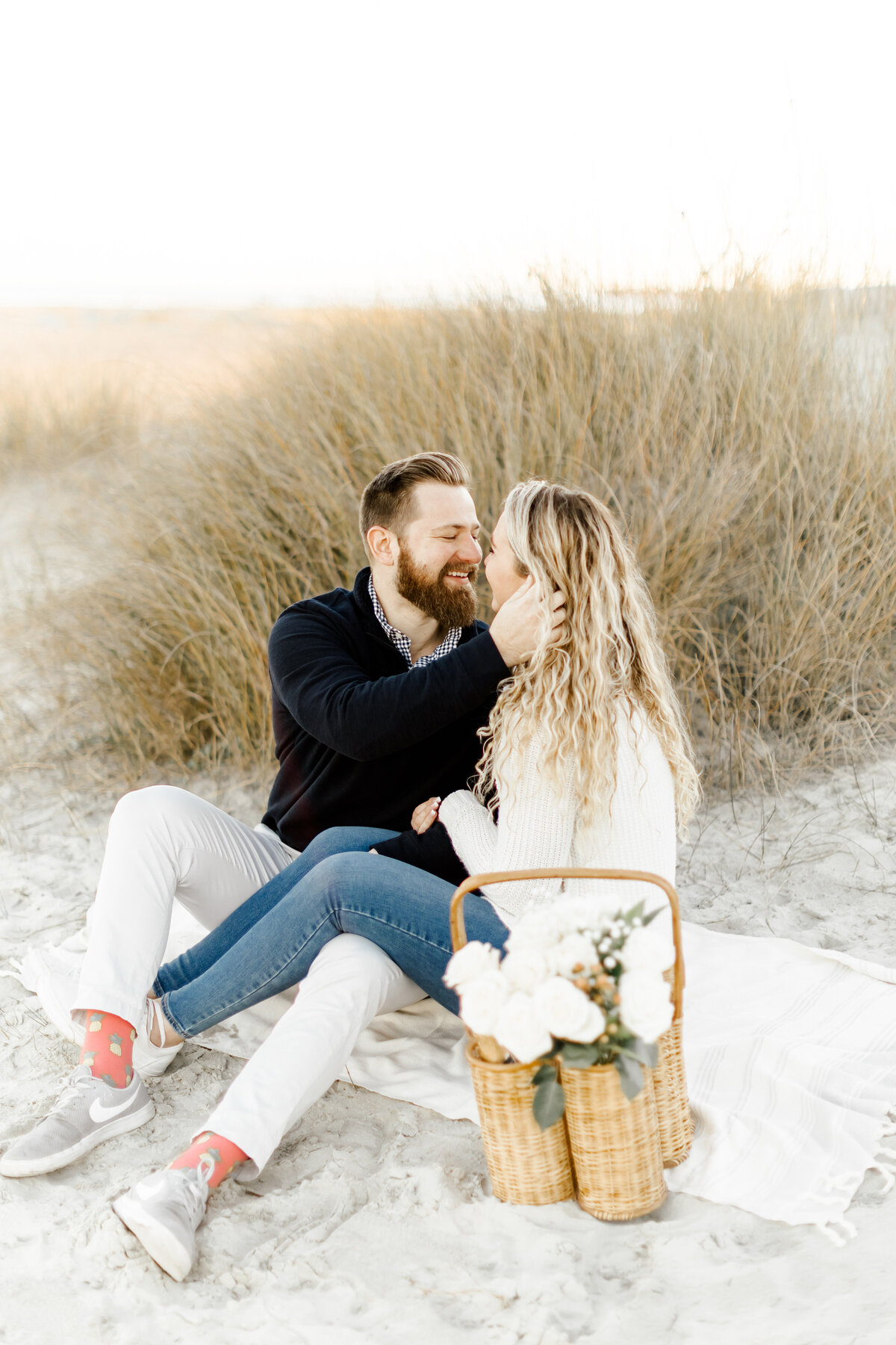 photo looking at each other sitting on picnic blanket on the beach taken by wedding photographers in orlando