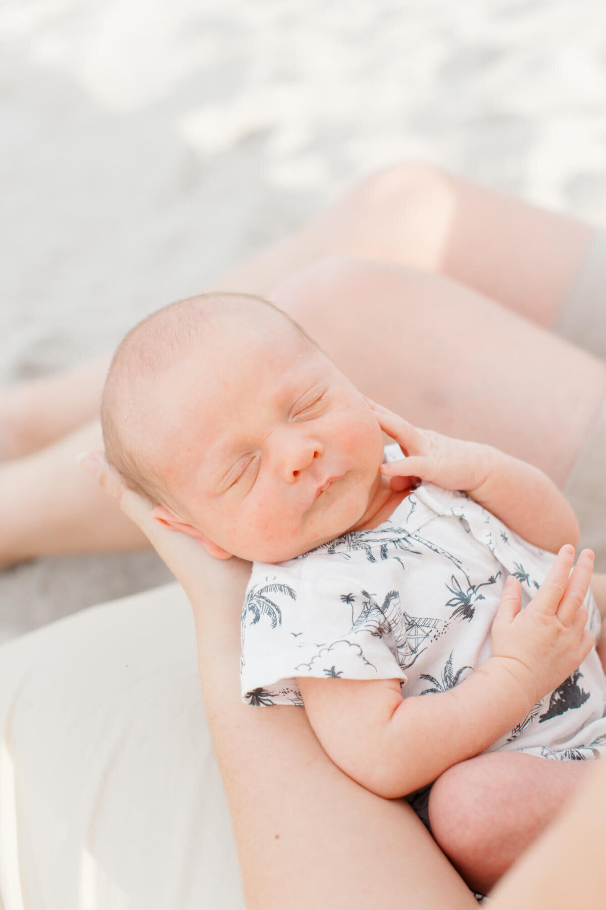 Closeup portrait of a newborn laying in his mothers arms at the beach