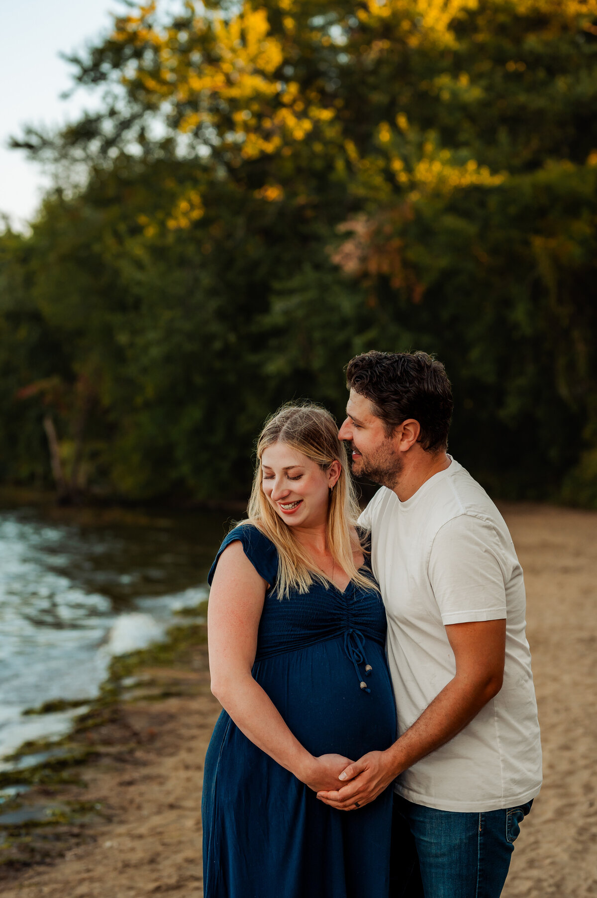 Couple smiling together by the river surrounded by autumn colours during Ottawa fall mini session.