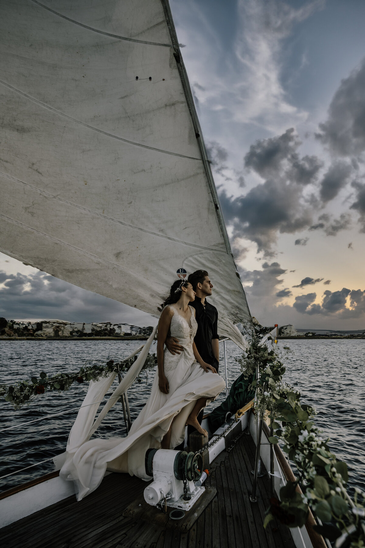 Bride and groom on yacht in San Diego looking out to the ocean at sunset holding each other close