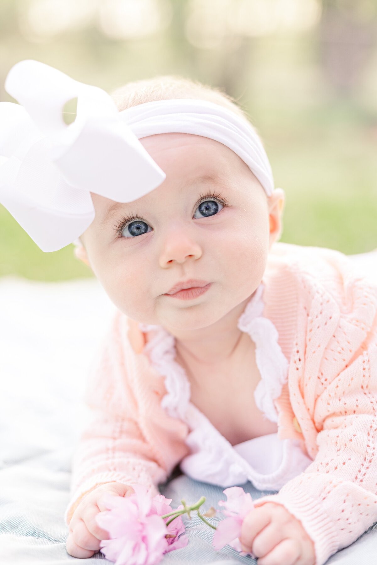 Close up of blue eyed baby holding a flower by an Ohio family photographer