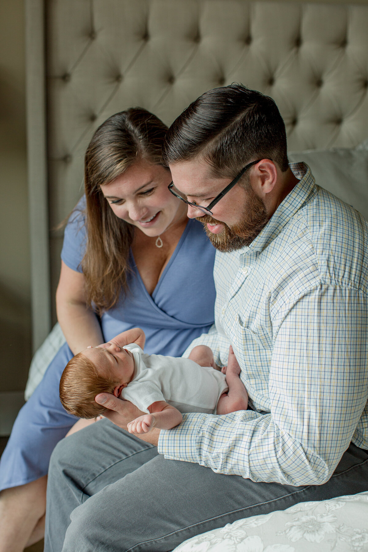 Family photo in Boone, NC of a man and woman holding their infant son in front of them and smiling during a newborn family session.