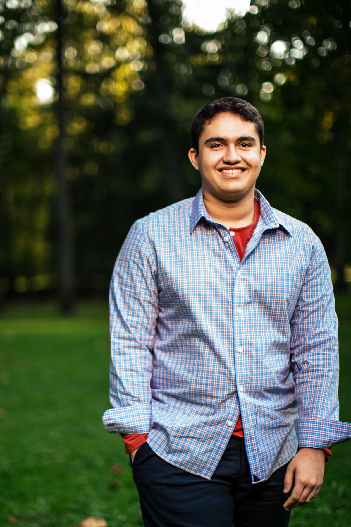 This brown skin boy walks through a park wearing a crisp Blue and white shirt during his photo shoot