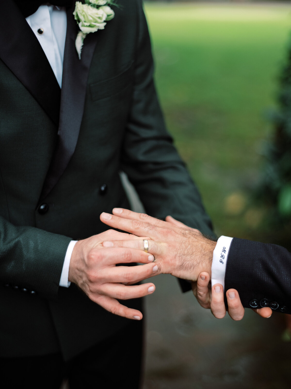 A heartfelt exchange of wedding rings among two grooms symbolizes their commitment, taking place in a lush garden, radiating love and unity on their special day.
