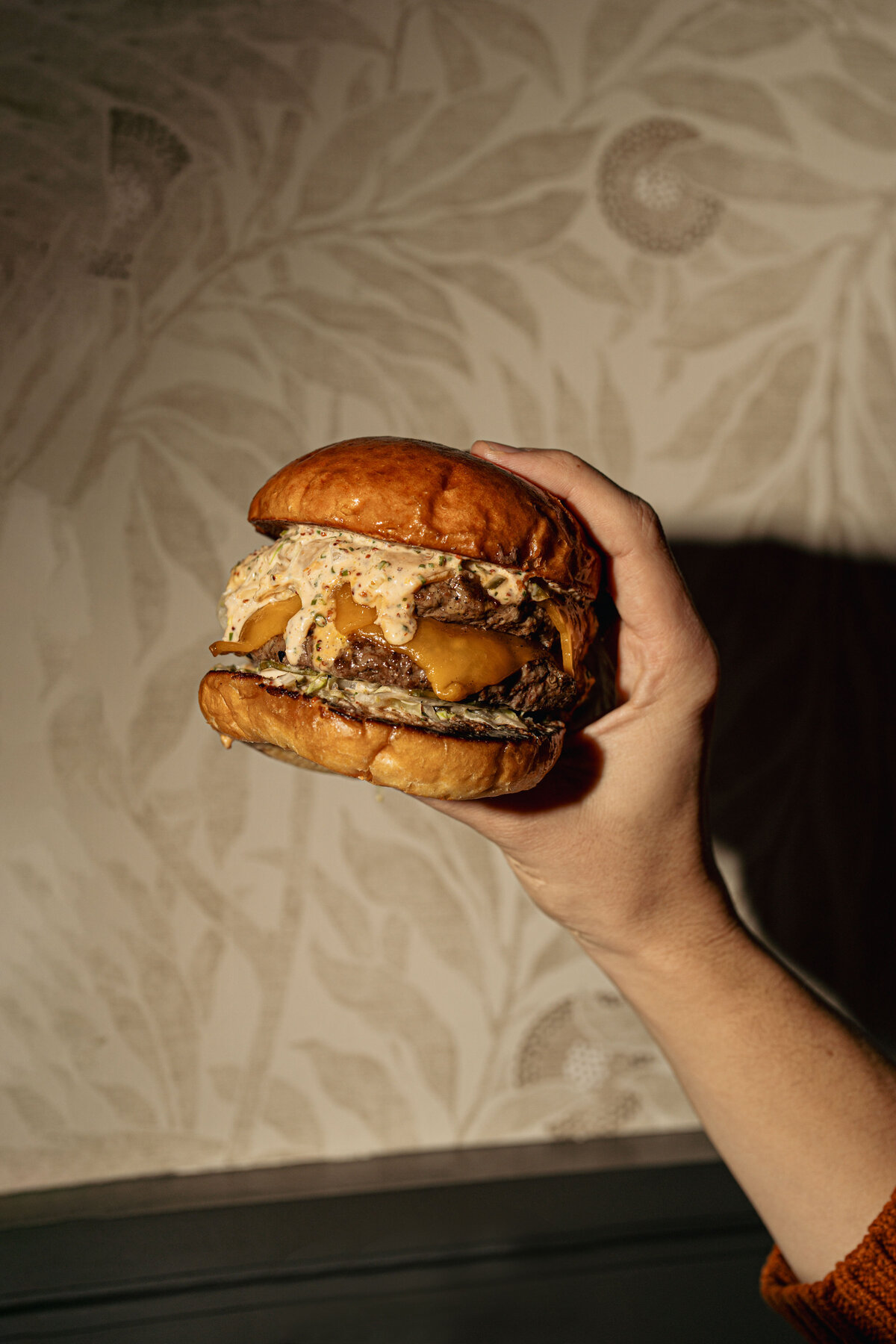 Food Photography in Greenville, SC featuring a sloppy burger in a man's hand.