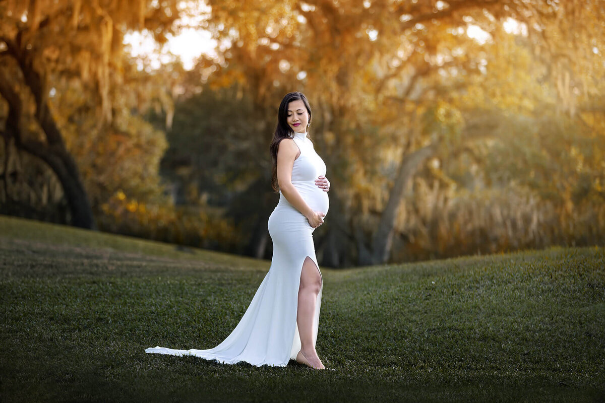 Beautiful expectant momma wearing a white, long dress during golden hour in Houston..