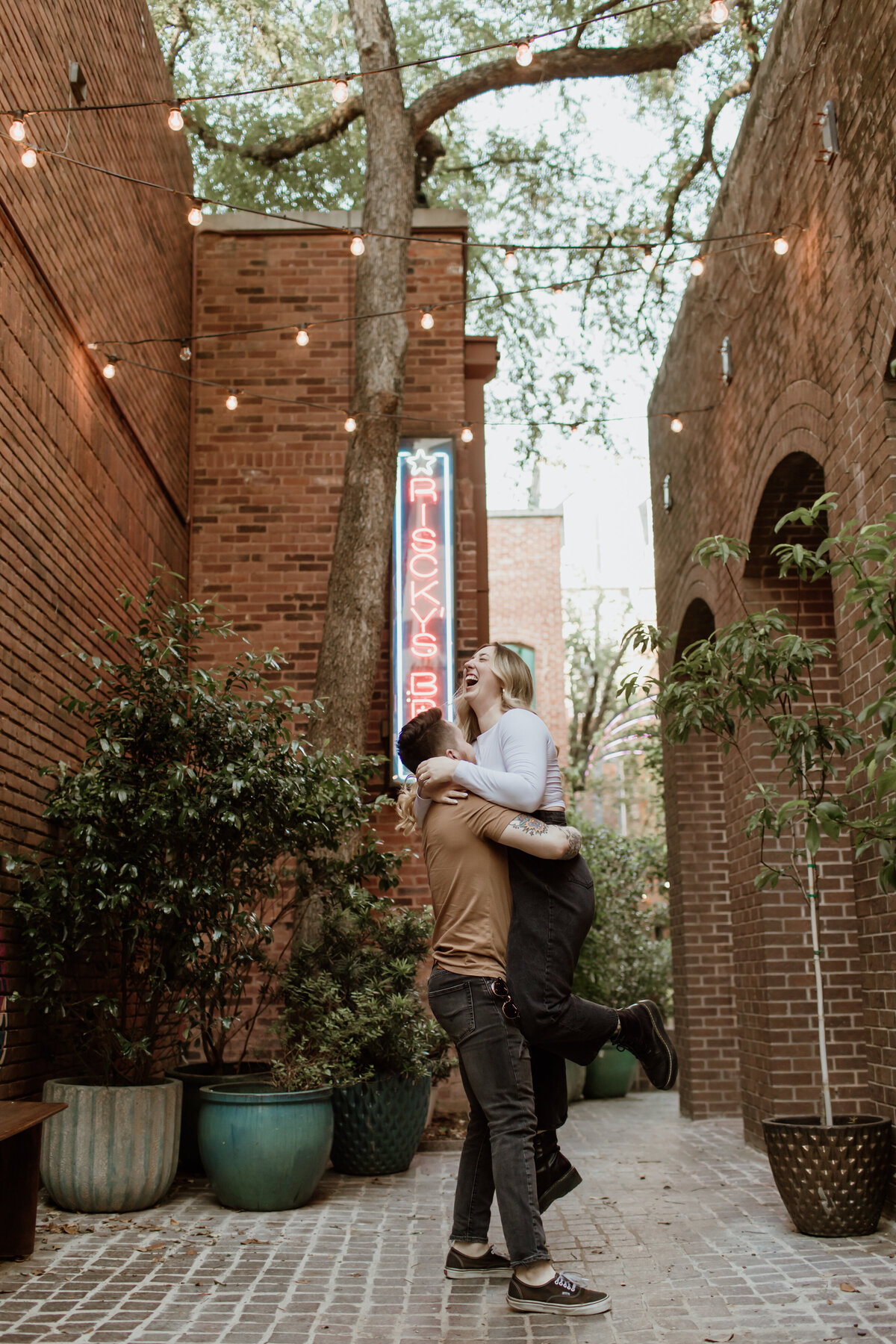 An engaged couple playfully embraces in Sundance Square in downtown Fort Worth by Fort Worth Wedding Photographer, Megan Christine Studio