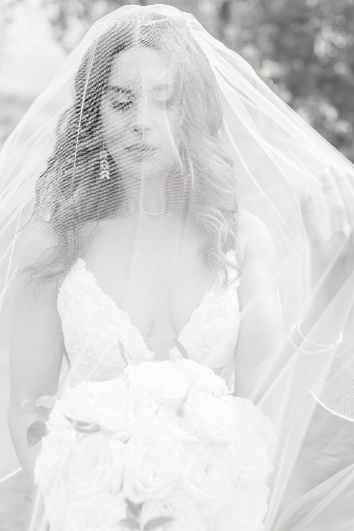 Bride with her veil covering her face in black and white