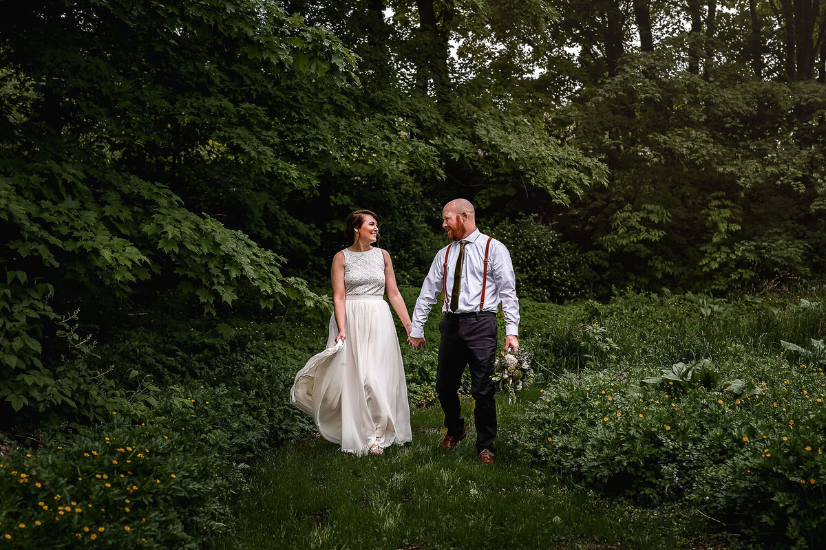 Bride and groom holding hands and chatting as they walk together in garden in Tamworth NH by Lisa Smith Photography