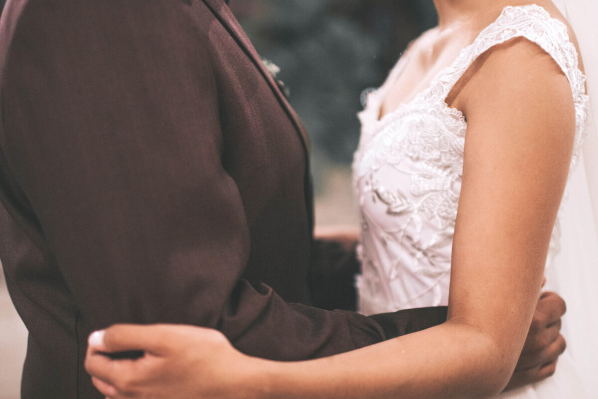 Bride and groom holding each others arms while facing each other