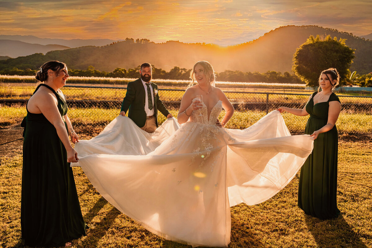 The bride and groom pose joyfully with their bridesmaids, illuminated by the warm glow of a beautiful sunset. - photo by Jamie Simmons