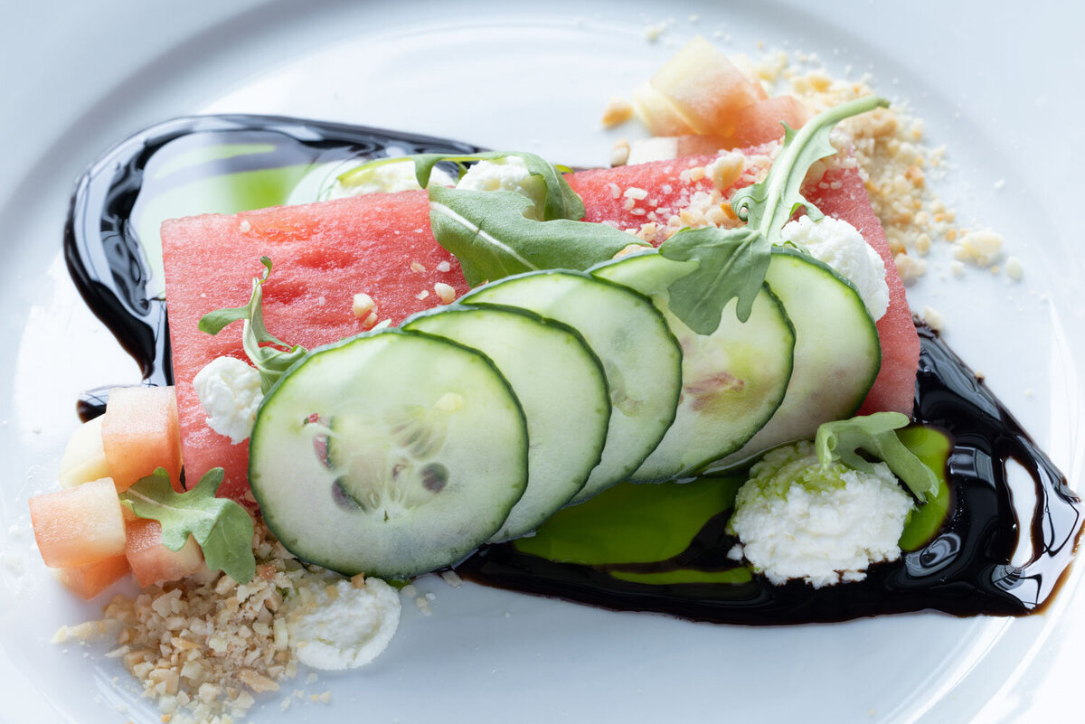 Watermelon slice topped with cucumber and crumbled cheese