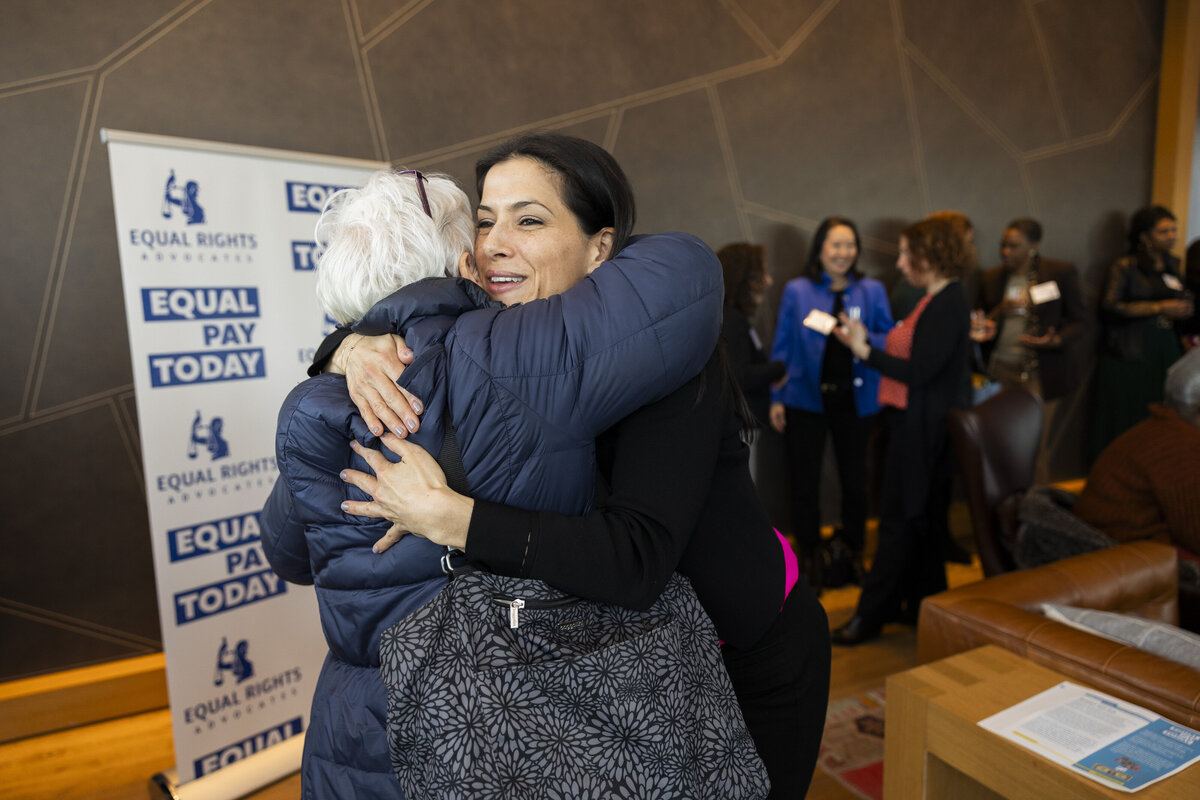 Two people go for a hug at the Equal Pay Today event.