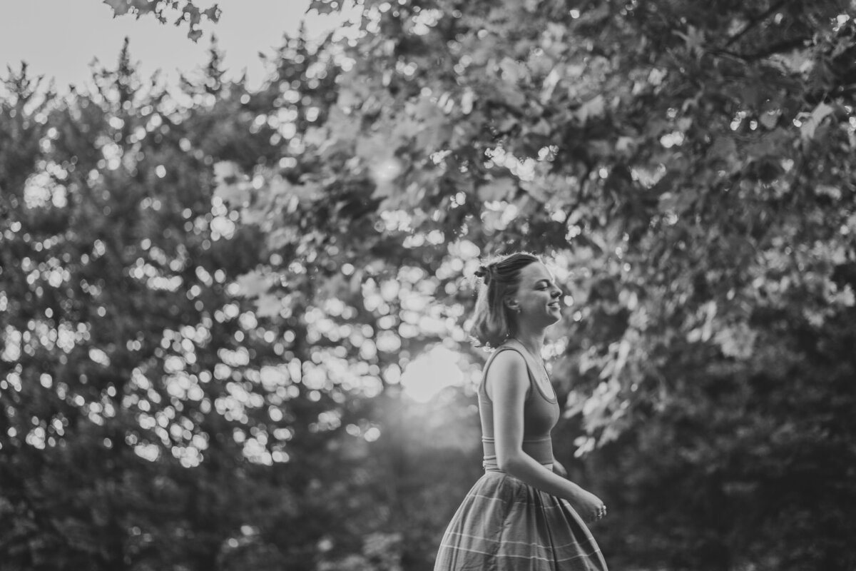 A person walks in front of a forested area.