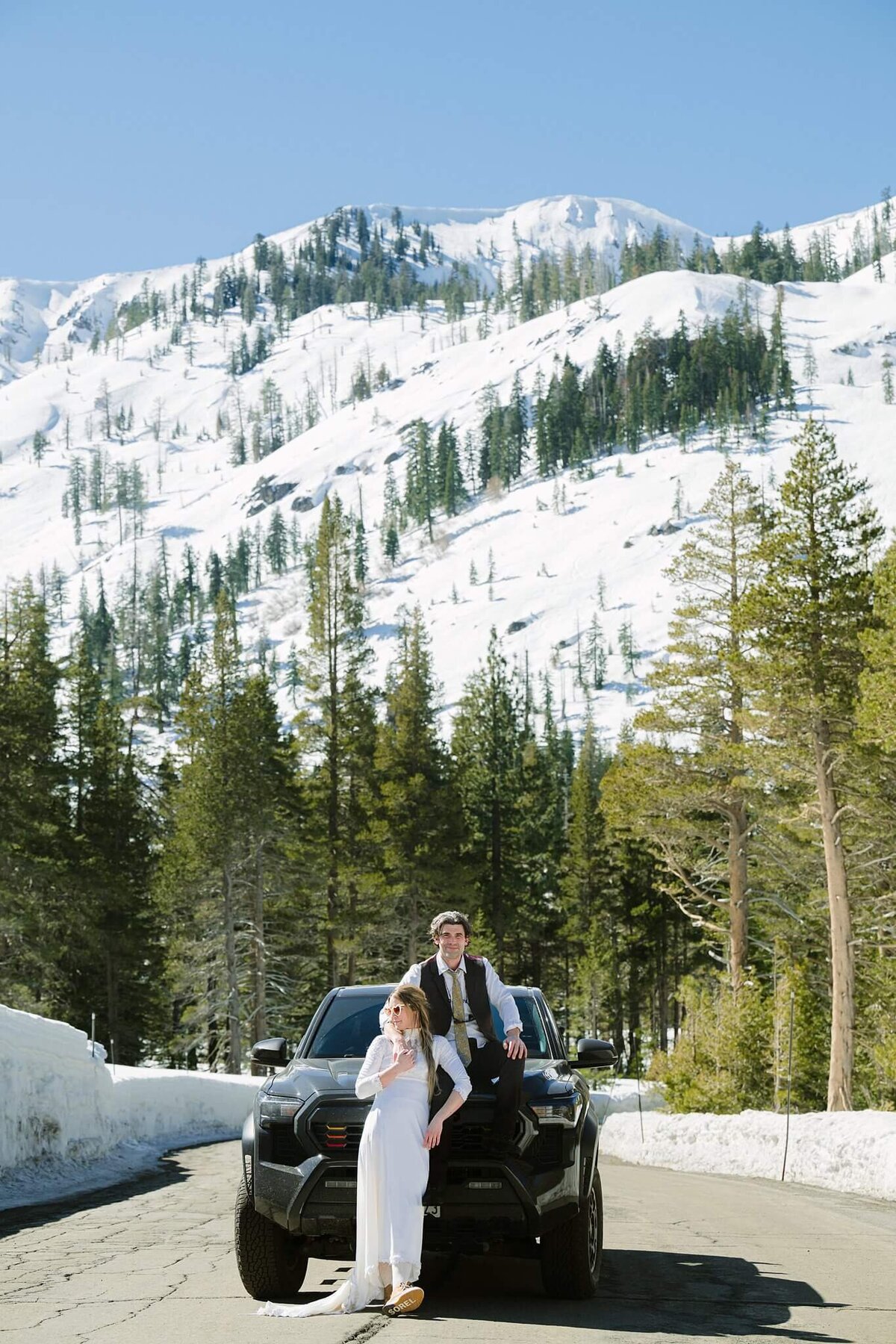 bride and groom posing on a tacoma during winter elopement in Palisades Tahoe Alpine with mountain views.
