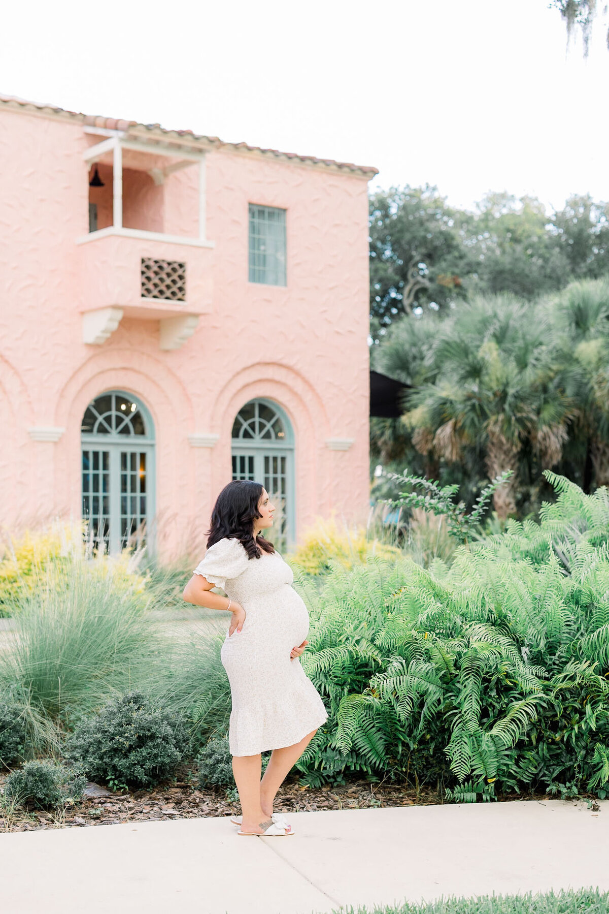 Pregnant woman standing in front of a pink building for Tampa maternity photographer Tina Marie Studio.