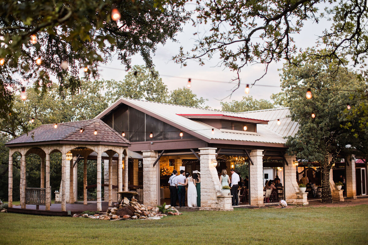 Outdoor wedding reception venue with string lights and guests