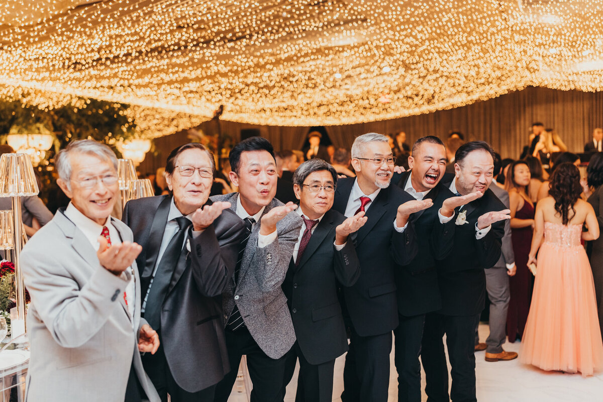 friends of groom all blow kisses at them, jokingly during the reception.