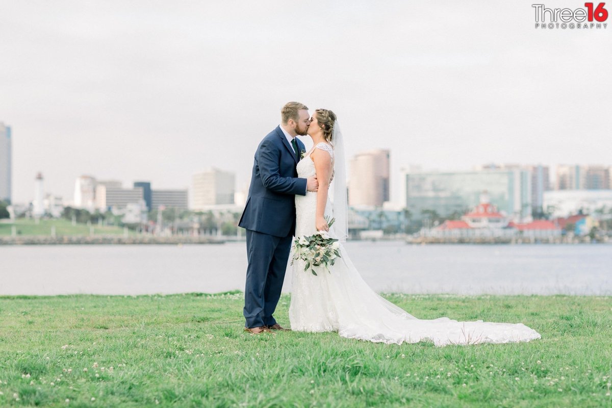 Groom kisses his Bride with the ocean in the background