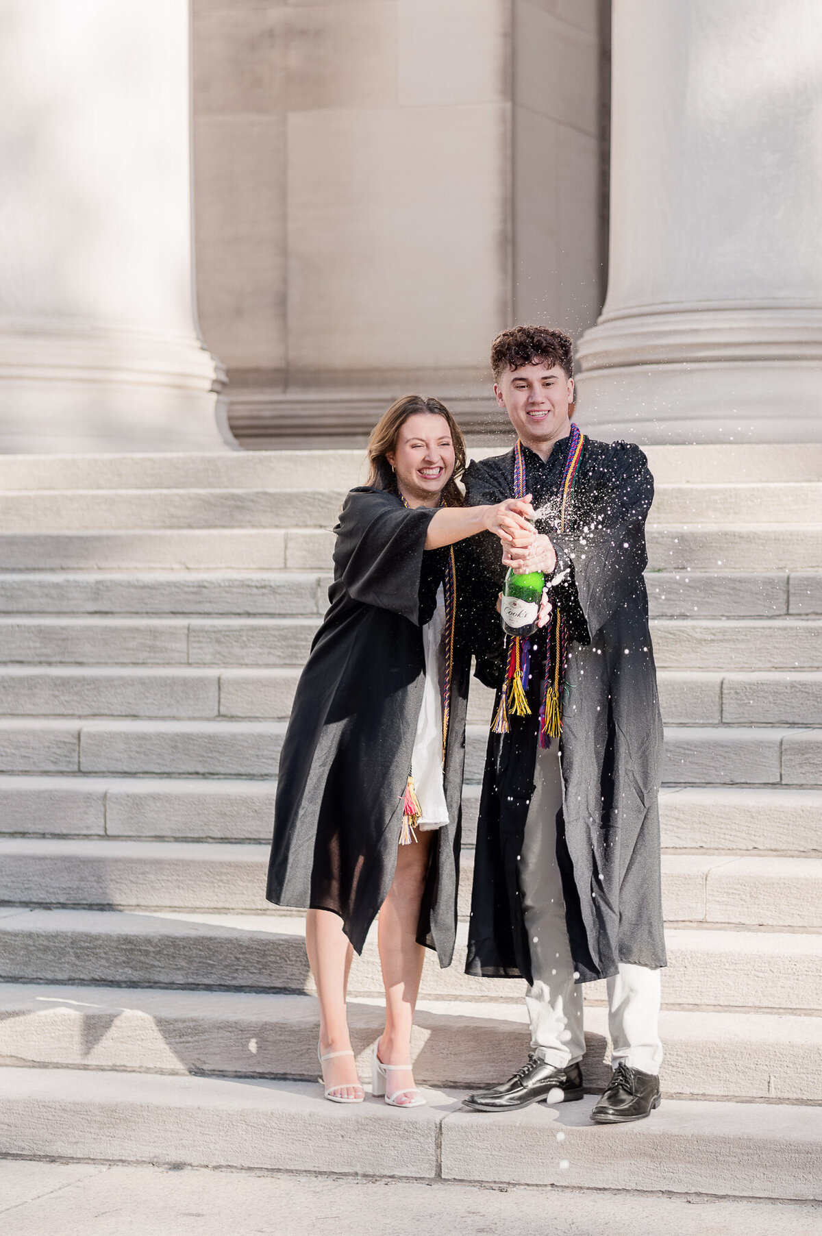 College senior popping champagne during a downtown Pittsburgh senior session — fun  photo by Lens Love Photography.