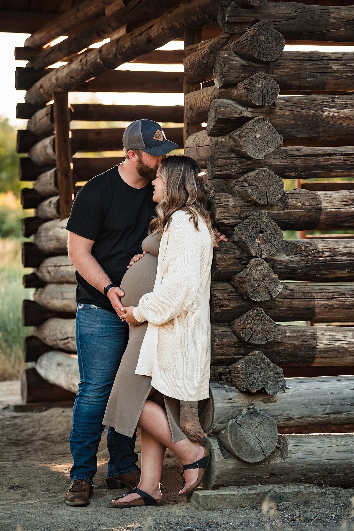 couple maternity photos against old barn
