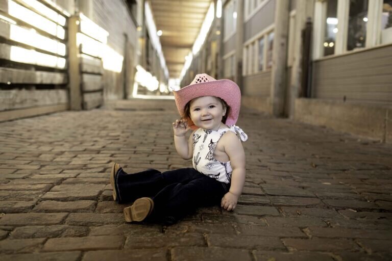 Birthday child striking a playful pose in their festive outfit, smiling and enjoying their fun birthday photoshoot in stockyards