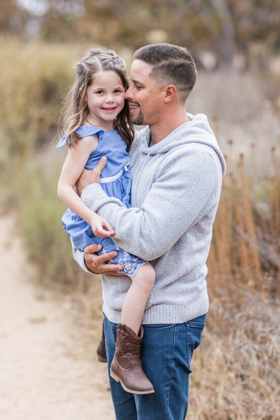 father-holding-daughter-in-field-sweetwater-river-bridge-san-diego