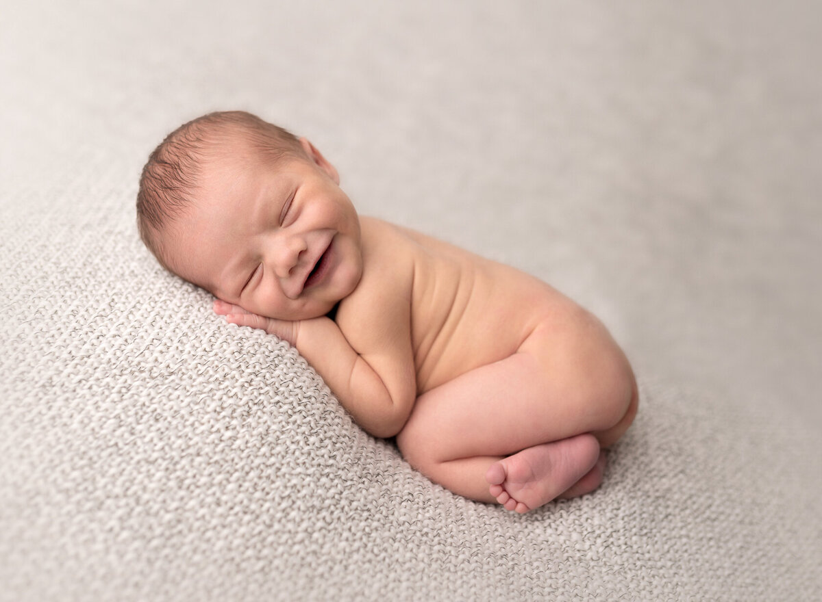 Smiling newborn photography in grey background by Houston Photographer